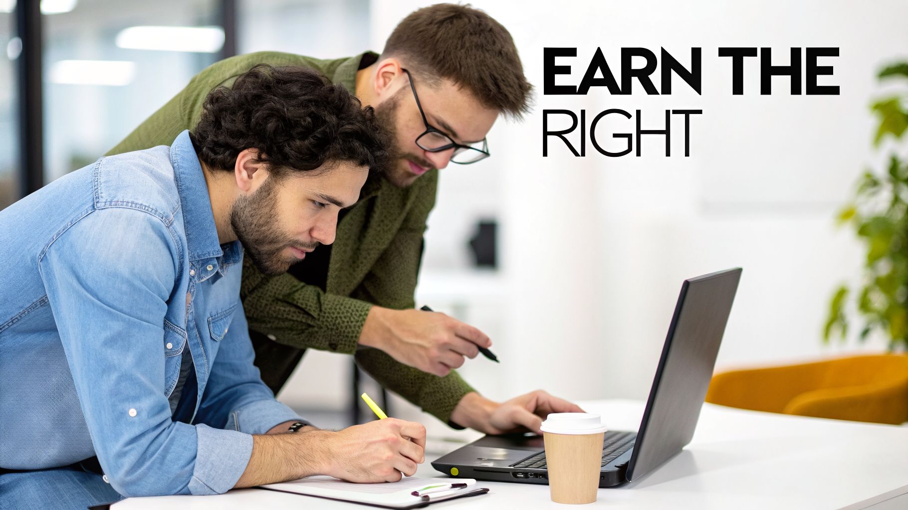 Two men collaborating intently on a laptop and documents, with motivational text "EARN THE RIGHT".